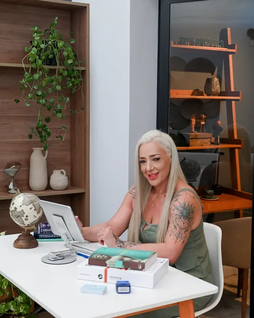 Consultório de Luciane Capassi com mesa de atendimento, estante e plantas